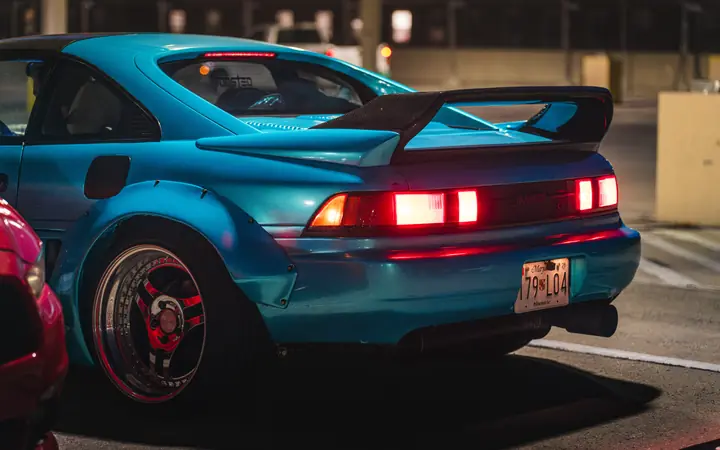 Blue Toyota MR2 in a parking garage with headlights on