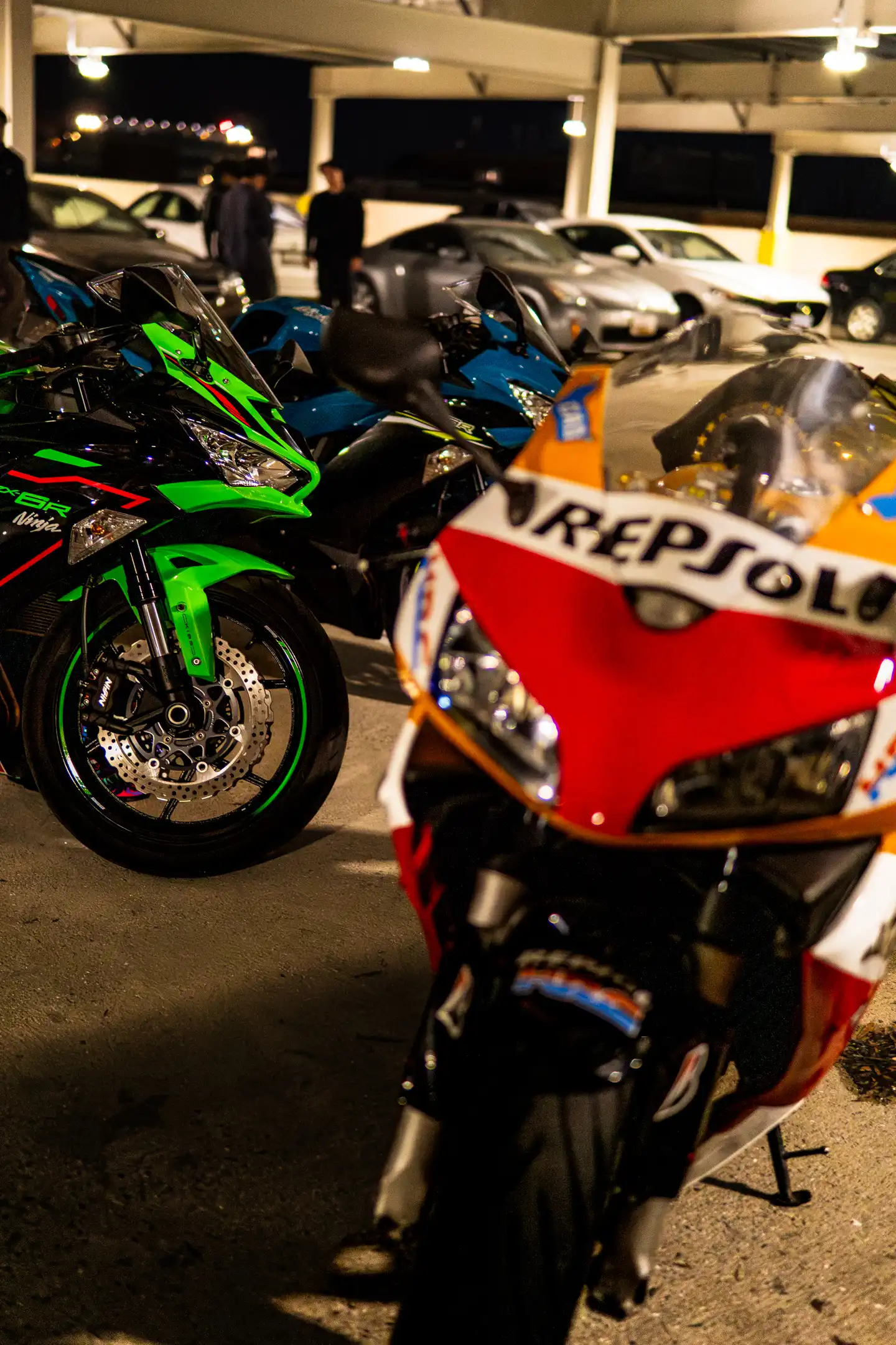 Three Motorcycles including Red and Orange Honda Repsol bike, Green Kawasaki Ninja ZX-10R, and Blue bike in parking garage in Maryland by Antlophotography