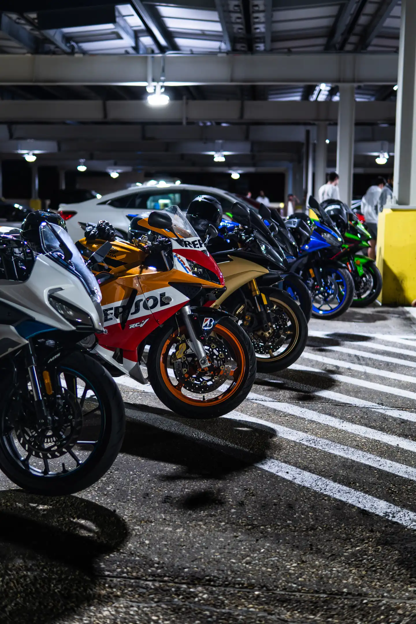 Vertical image of Six Motorcycles Lined up in parking garage by Antlophotography