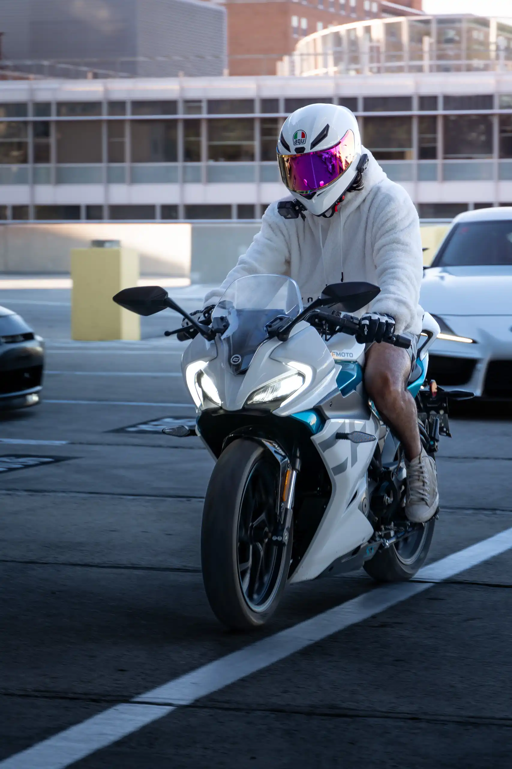 White and blue CFMoto 300SS Motorcycle with a white supra following behind driving in parking garage in Maryland by Antlophotography